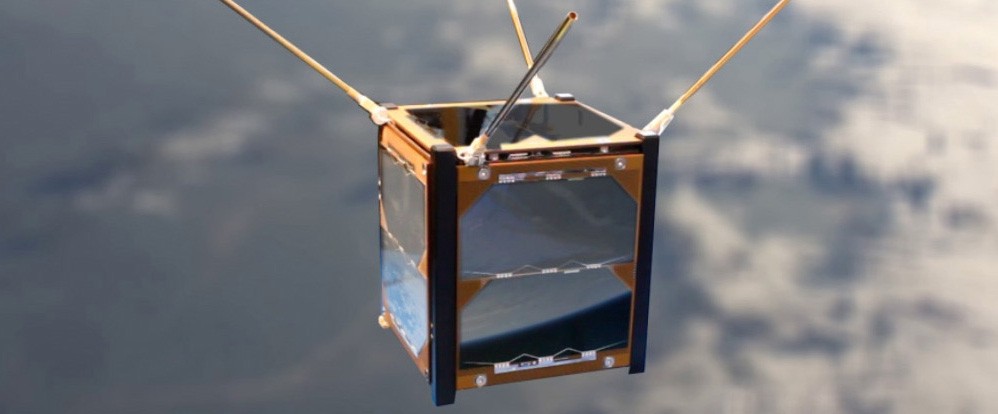 A cube-shaped satellite, orbiting Earth, with four small antennae emerging from the top.