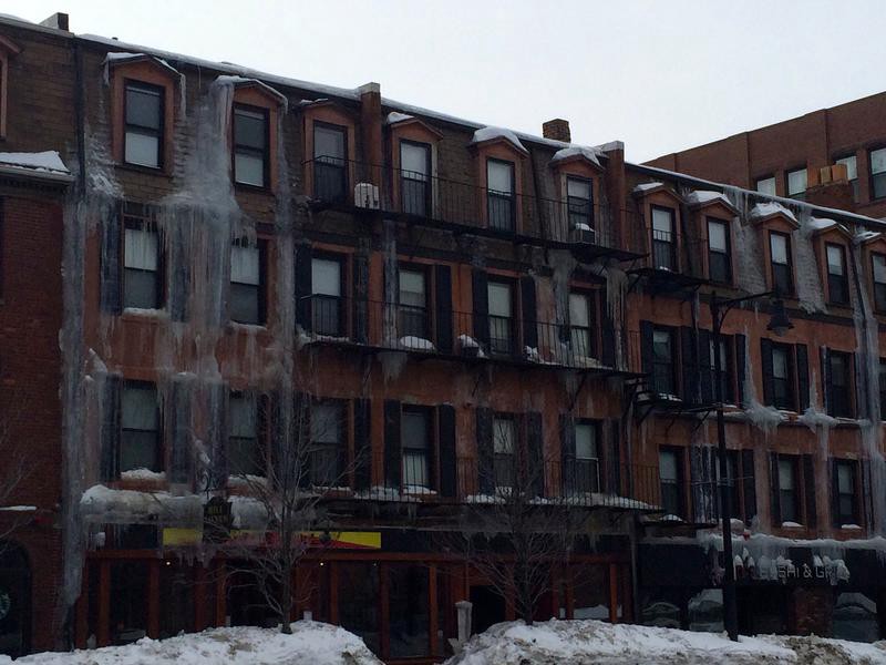 An apartment block with frozen water down the front and over the windows, from broken pipes.