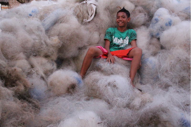 A boy sits on a giant pile of bales.