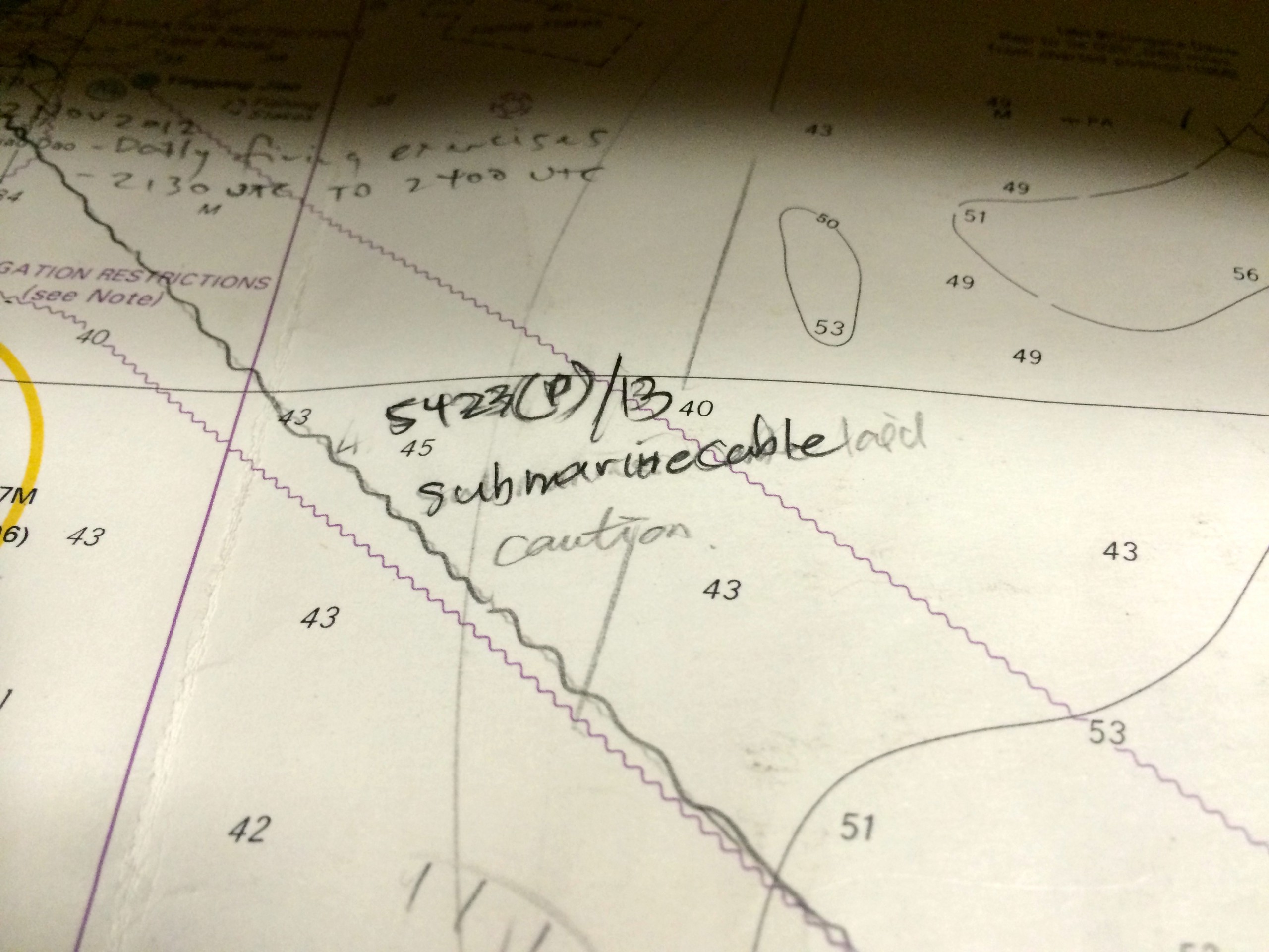A nautical navigation map with scribbled notes on it, indicating the location of an undersea cable.