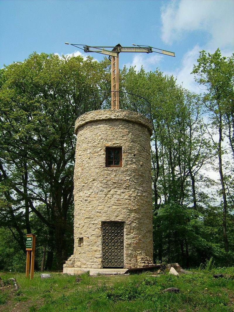 A stone tower with large semaphore arms on top of it.