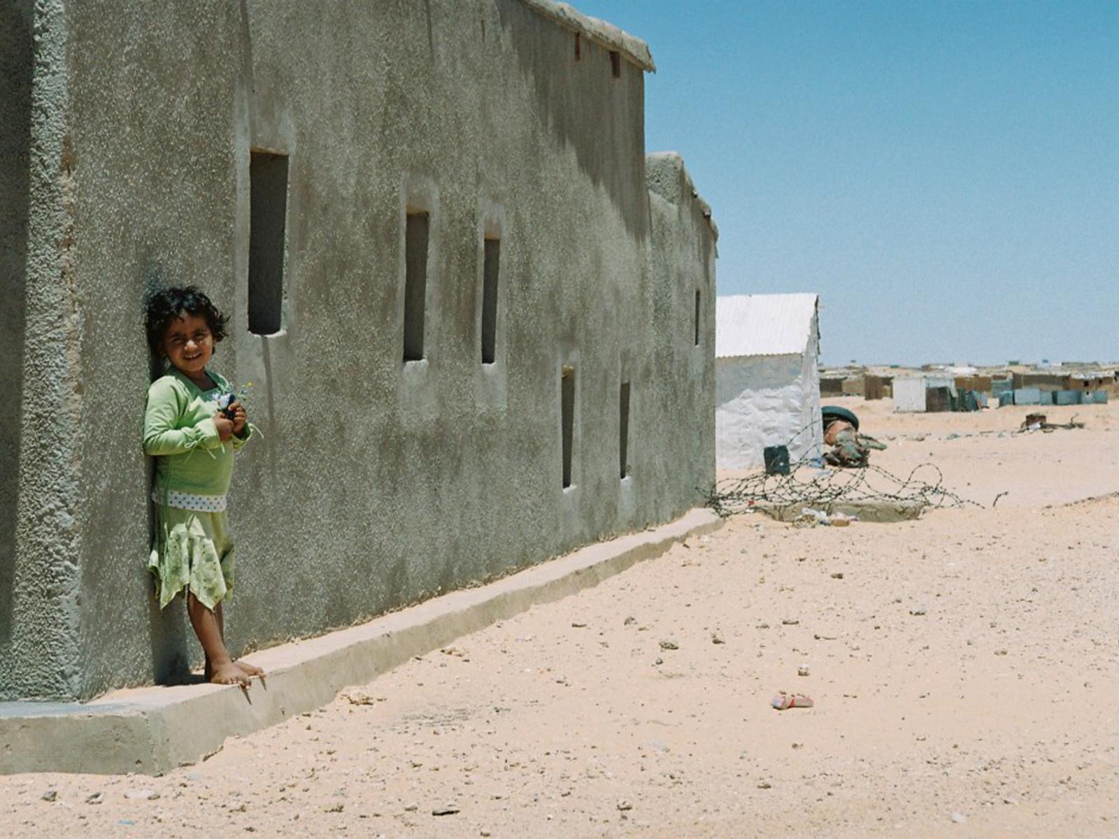 A Saharawi child stands outside her home in her desert village.