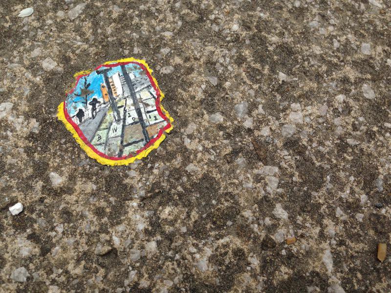 More chewing gum. This gum looks like a view of a city sidewalk with figures walking, lampposts, and buildings in the distance.