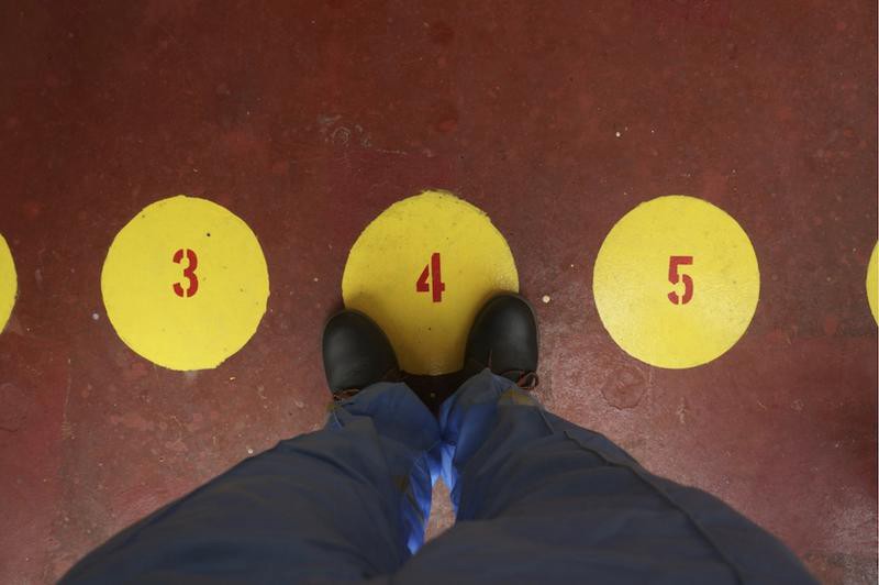 A pair of feet standing on a yellow circle with the number 4 on it. There is a line of such circles in a row, each with a different number from 1 to 12.