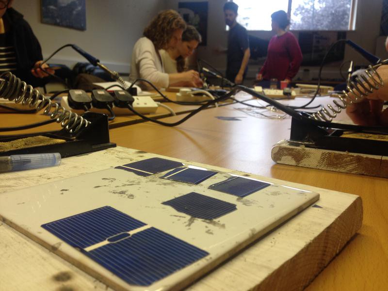 A table laid out with solar cells and soldering irons.