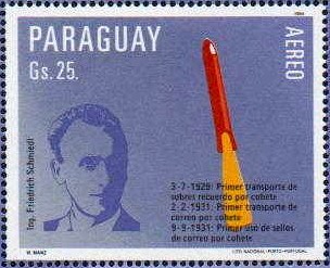 A blue-purple stamp. Schmiedl's portrait is on the left, while on the right is a red rocket flying through the sky.