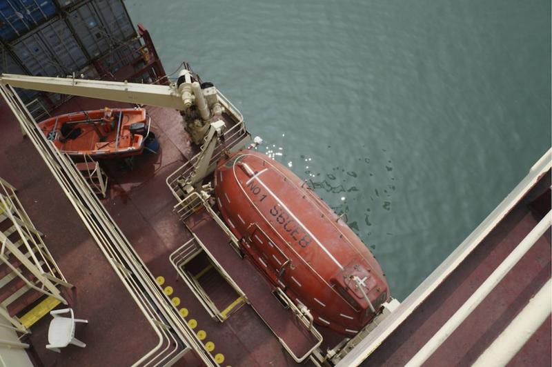 A lifeboat attached to the side of a large container ship.