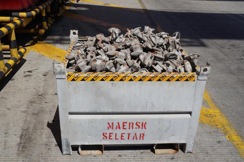 A pile of discarded twistlocks in a metal bin.