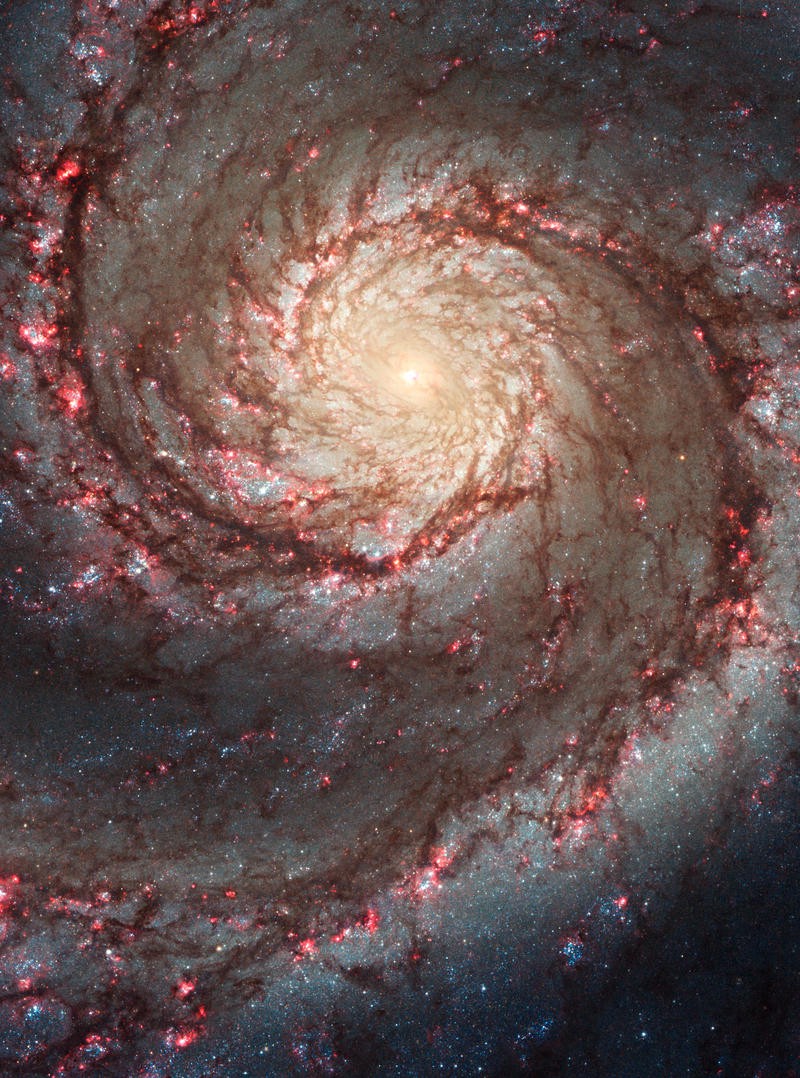A spiral galaxy, its center glowing bright yellow, its arms a mix of silver and red.