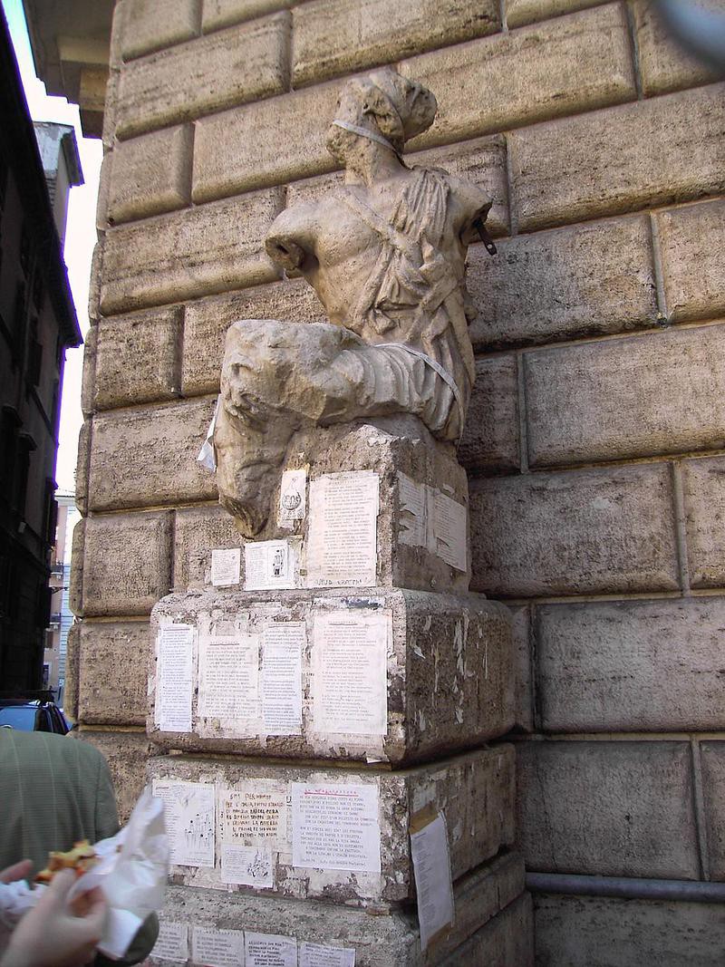 An old Roman statue (lacking arms and legs) sitting on a podium, covered in notes.