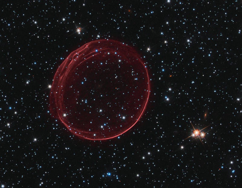 A faint red circle against a starry background.