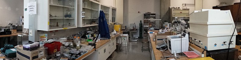 A messy lab with equipment on the worktops.