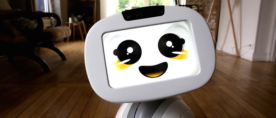A robot with a tablet computer for a head. The screen displays a smiling cartoon face.
