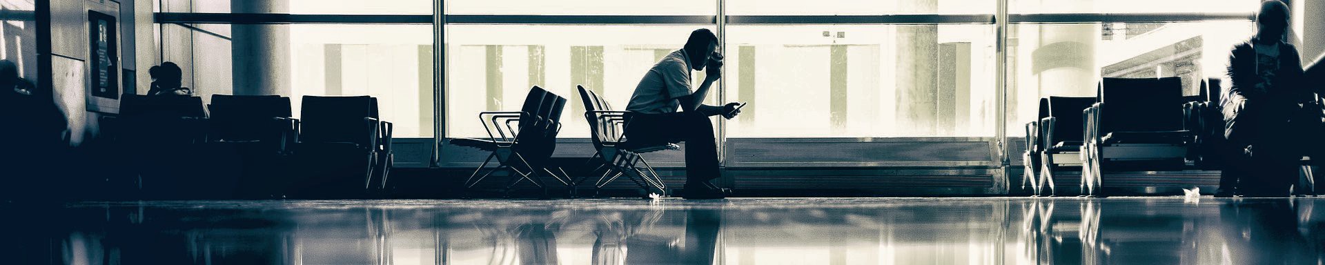 A man sits drinking coffee in an airport.