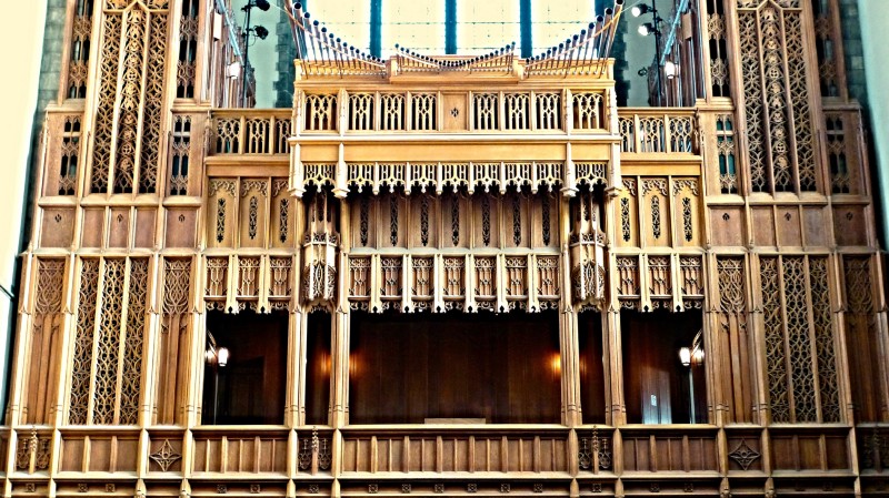 A large ornate church organ taking up the wall of a chapel.