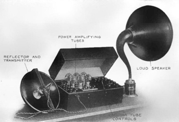 A box with vacuum tubes and a large dish mouthpiece, connected to a record player-like amplifying horn.