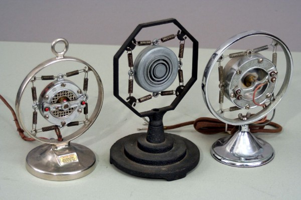 A collection of primitive microphones, made of metal plates suspended in the center of circular frames with springs.