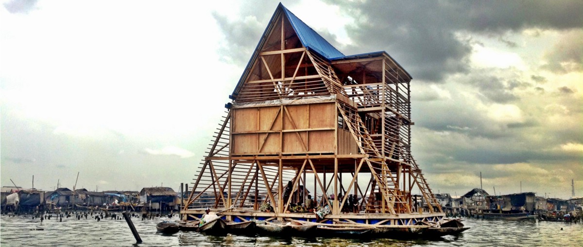 A triangular wooden structure floating on pontoons in a bay.