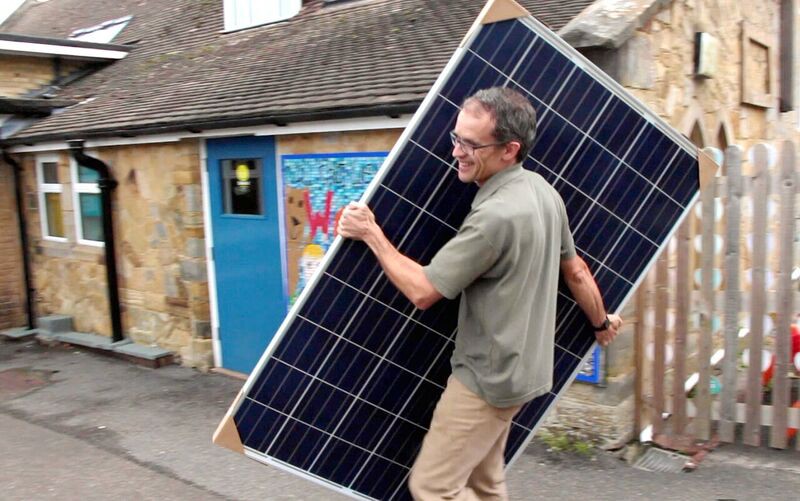 A man carries a solar panel.