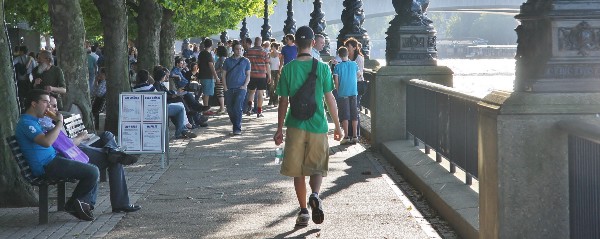 Pedestrians walk along the embankment alongside the River Thames.