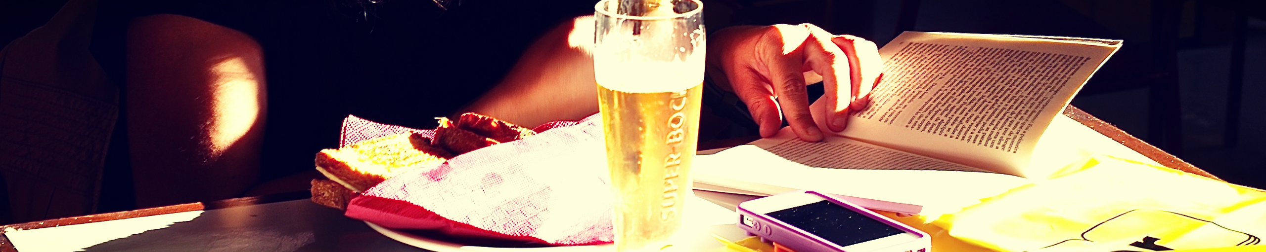 A book and a beer and a sandwich.