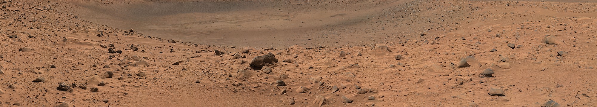 A photo from the surface of Mars, showing boulders and stones in a valley depression.