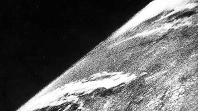 A black and white photograph showing clearly the edge of the Earth against the blackness of space, with clouds on the planet's surface.