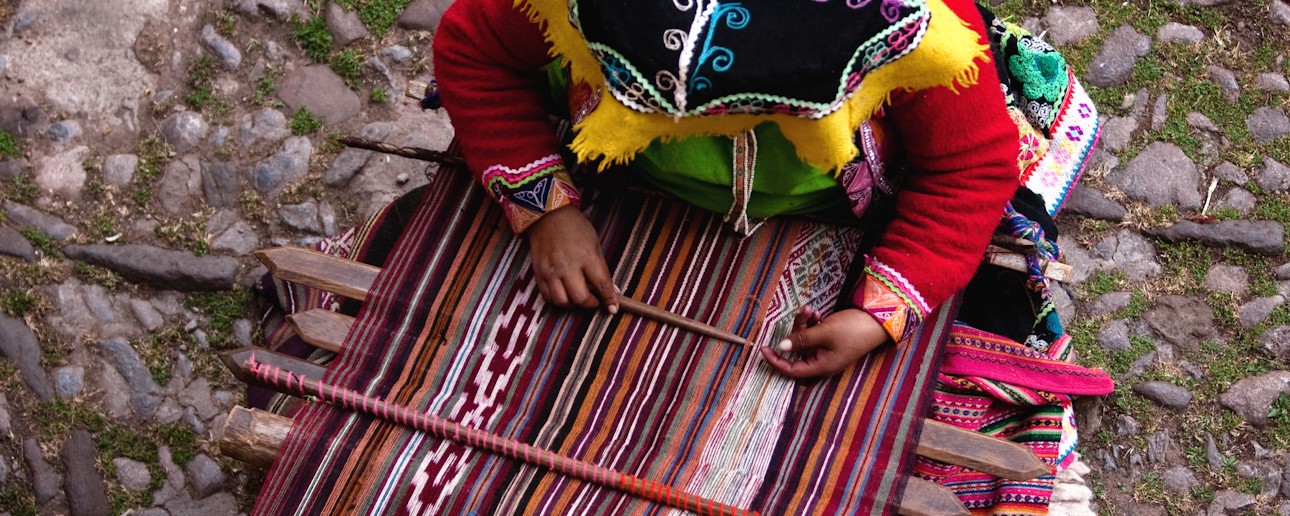 A woman weaves fabric.