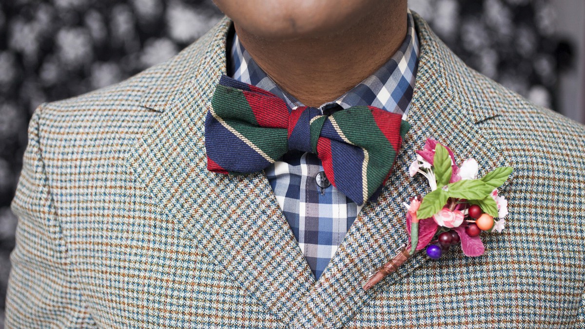 A close-up of a bow tie around someone's neck. They're also wearing a suit.