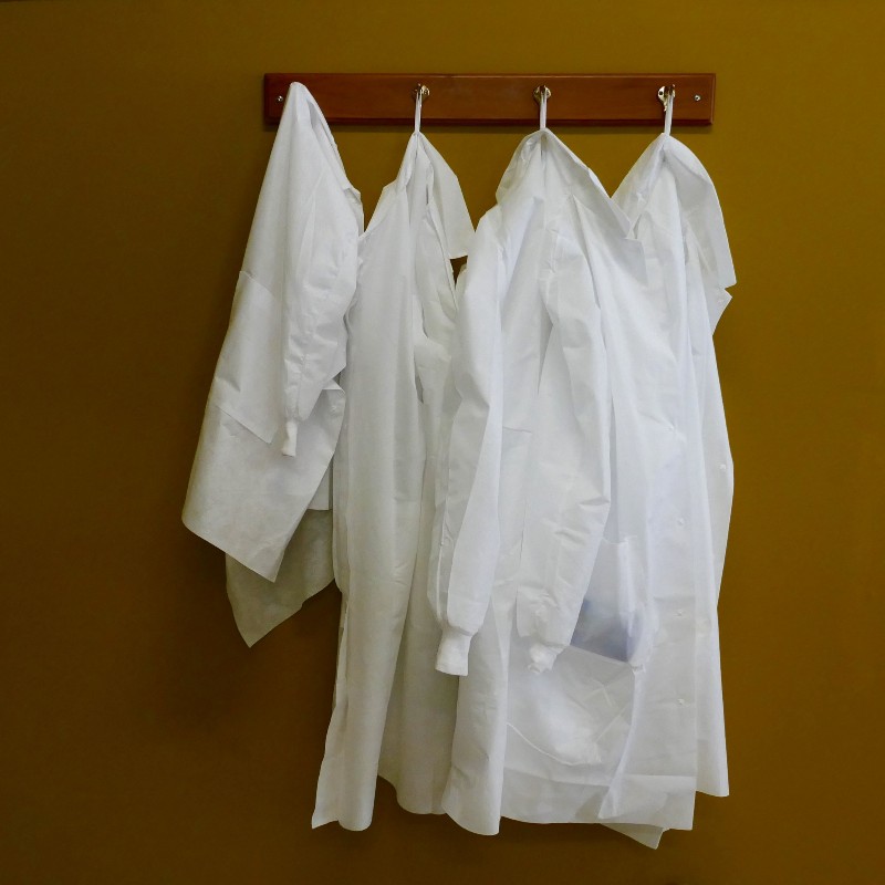 White coats hanging on coatroom hooks.