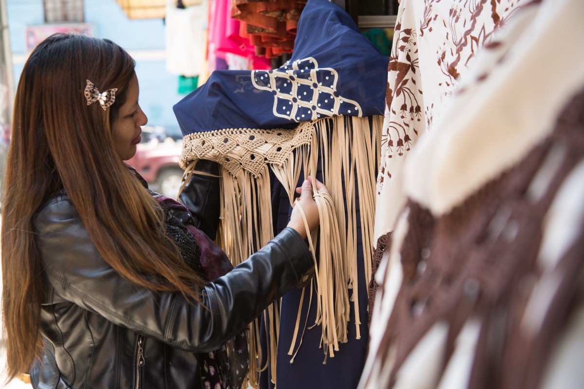 A woman inspects some Aymara fabrics at a market.