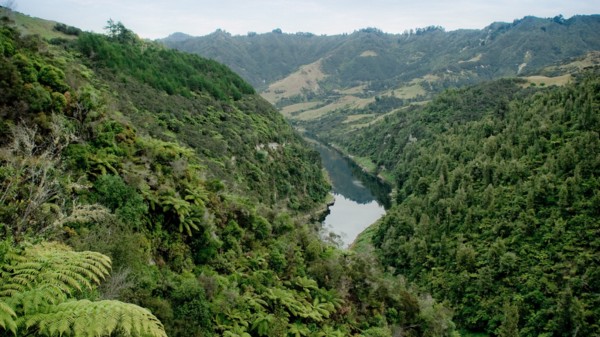 A river passes between two steep, forested hills.