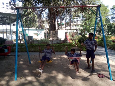 Children in India play on a swing.