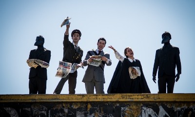 Protesters in costume throw leaflets from the top of a building.