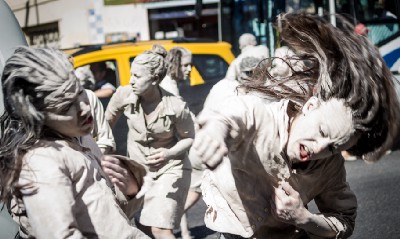 Protesters covered in white paint hold a mock fight in the street.