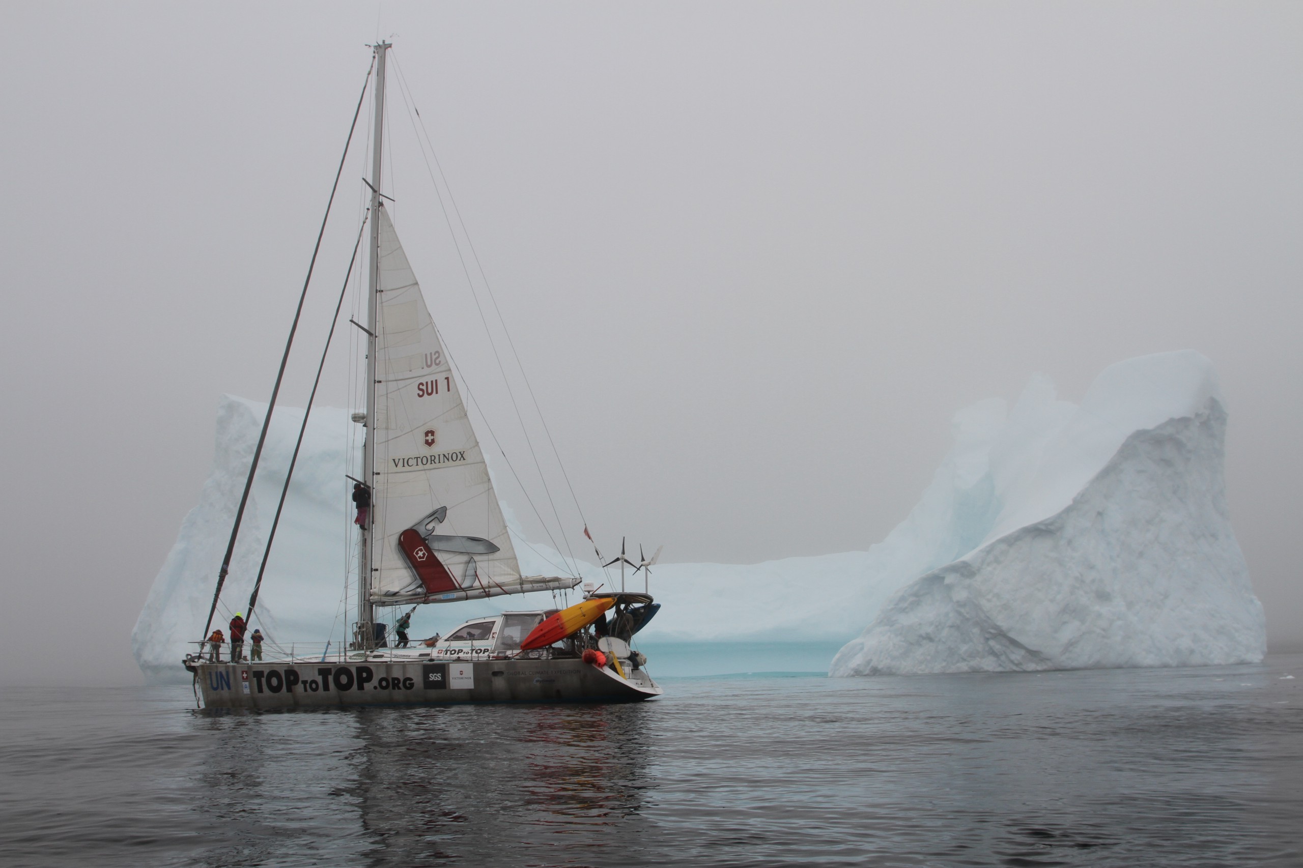 A sailboat in front of a large block of ice