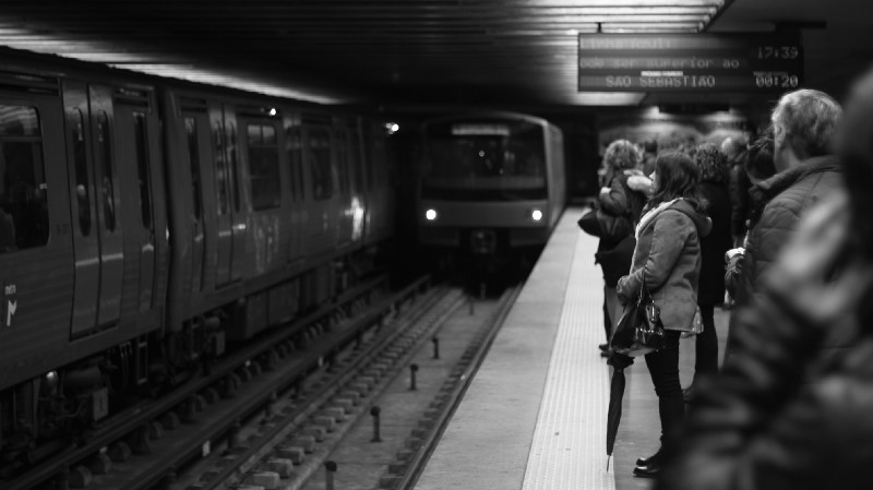 Passengers wait at a subway station to board a train.