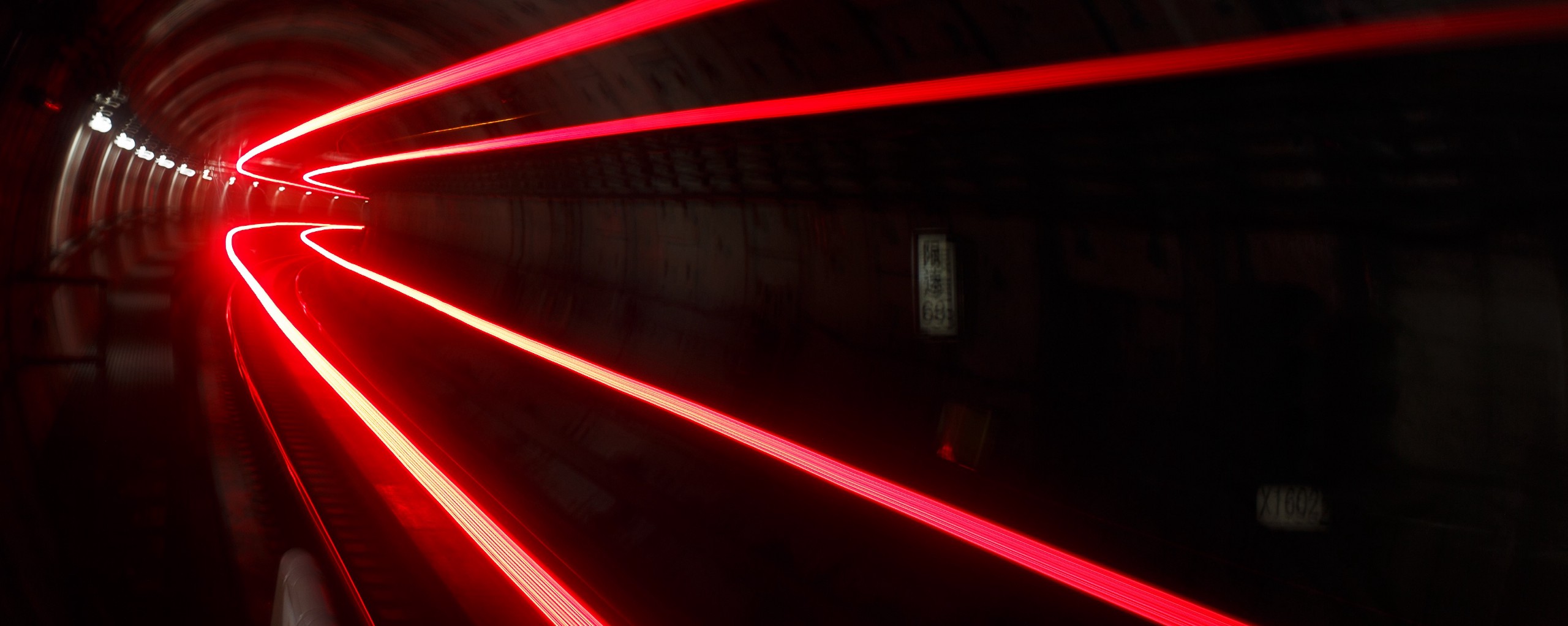 A timelapse photograph in a train tunnel, with red light trails showing where trains have passed through.
