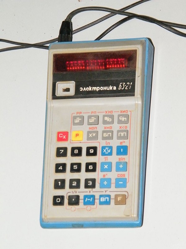 A yellowing grey-blue calculator with a power lead.