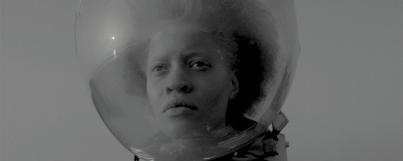 A black woman wearing a space helmet.