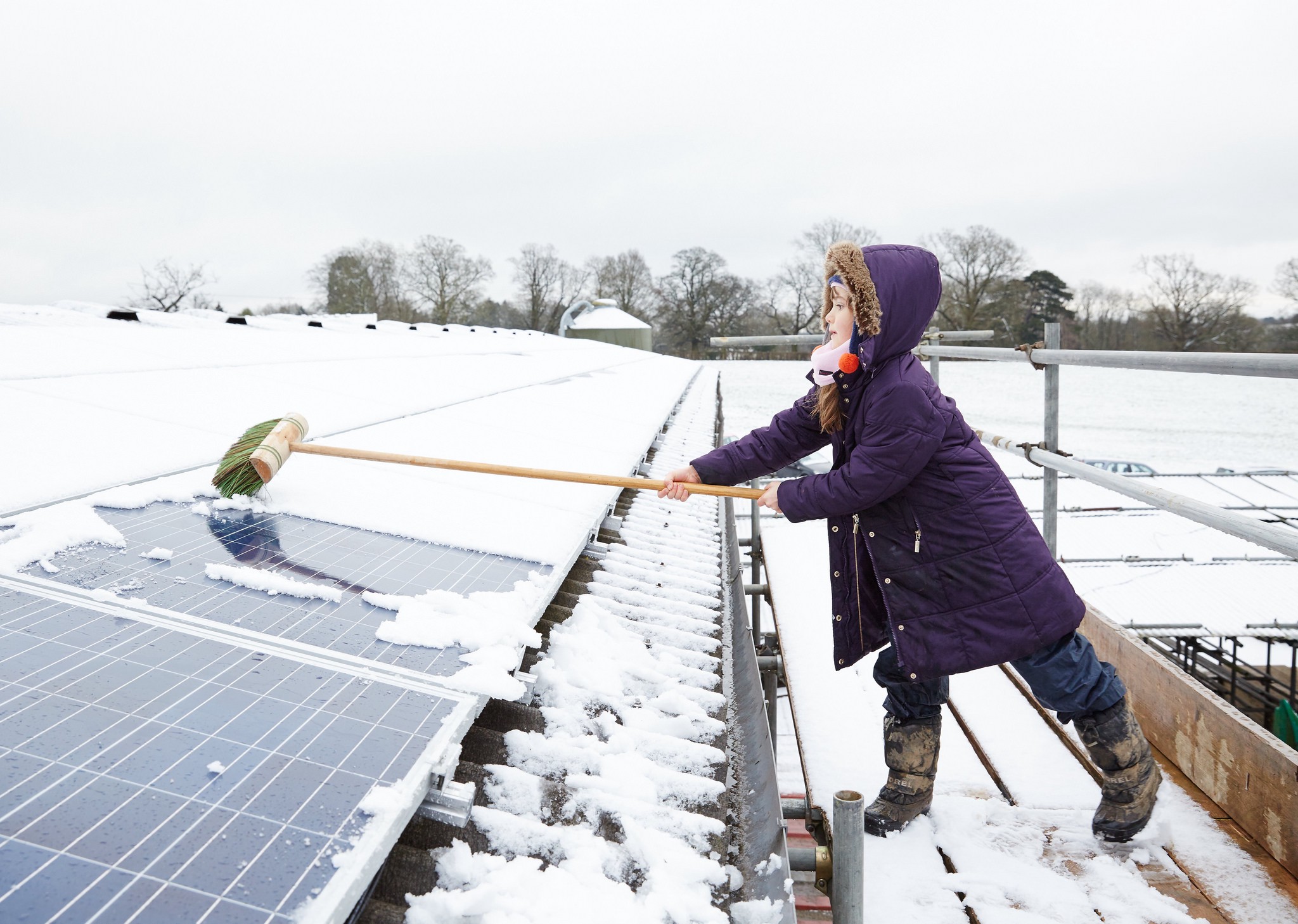 A child brushing snow off solar panels