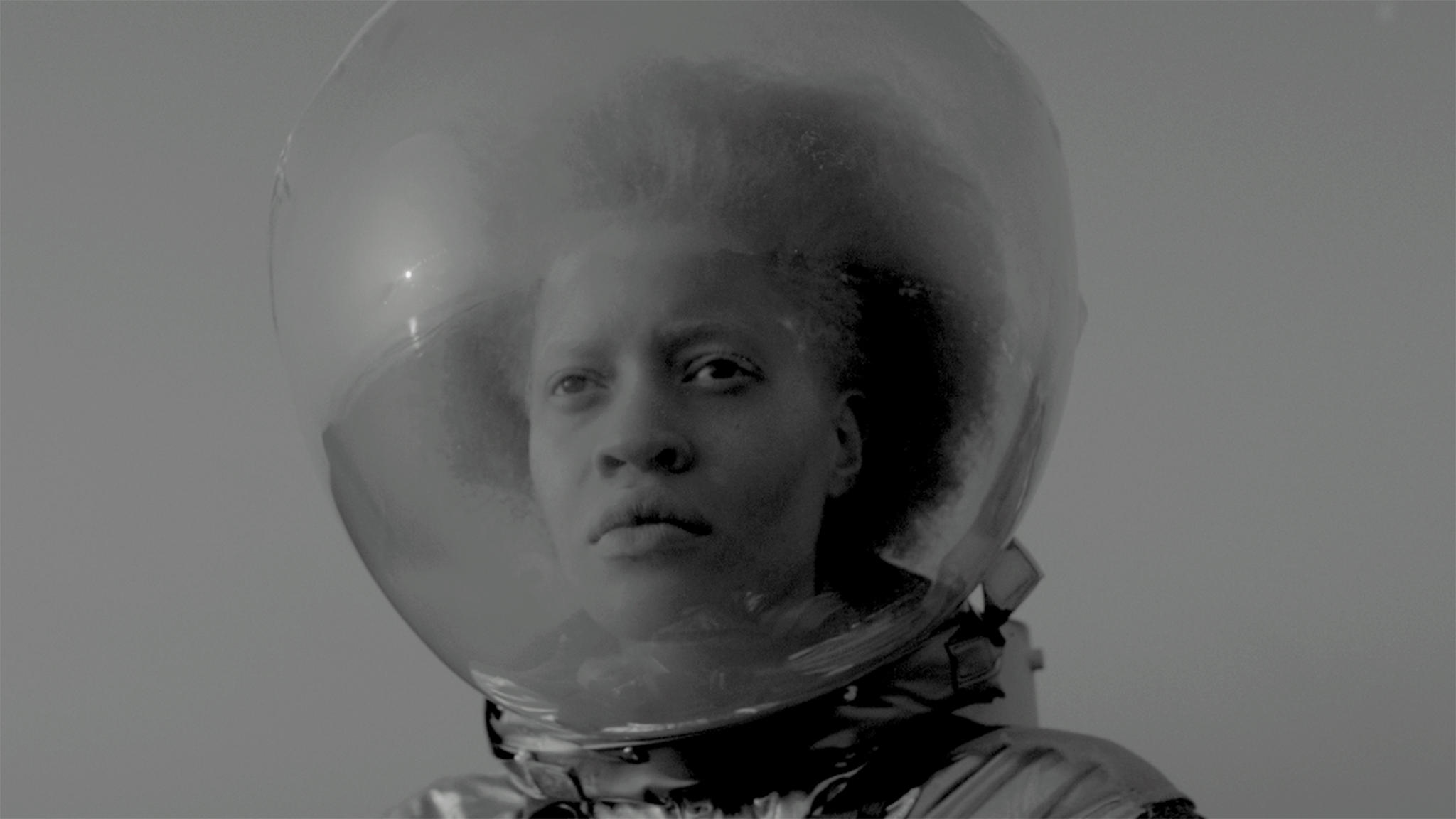 A black-and-white still image of an astronaut in a suit from the film 