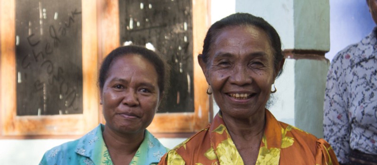Two Indonesian women smile into the camera.